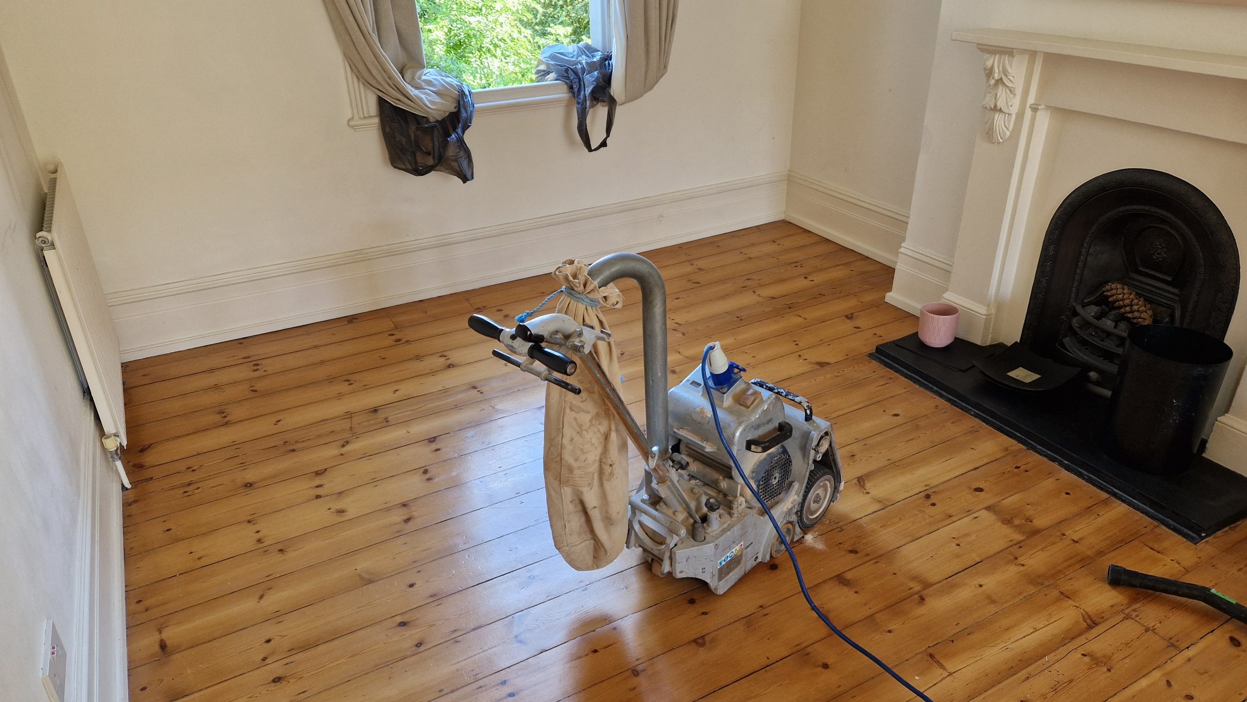 Eco-Friendly Wood Floor Sanding in London: Isleworth Softwood Pine Floorboards Mid-Renovation Eco-Friendly Wood Floor Sanding in London – Isleworth living-room softwood pine floorboards being restored with a dust-free belt sander.