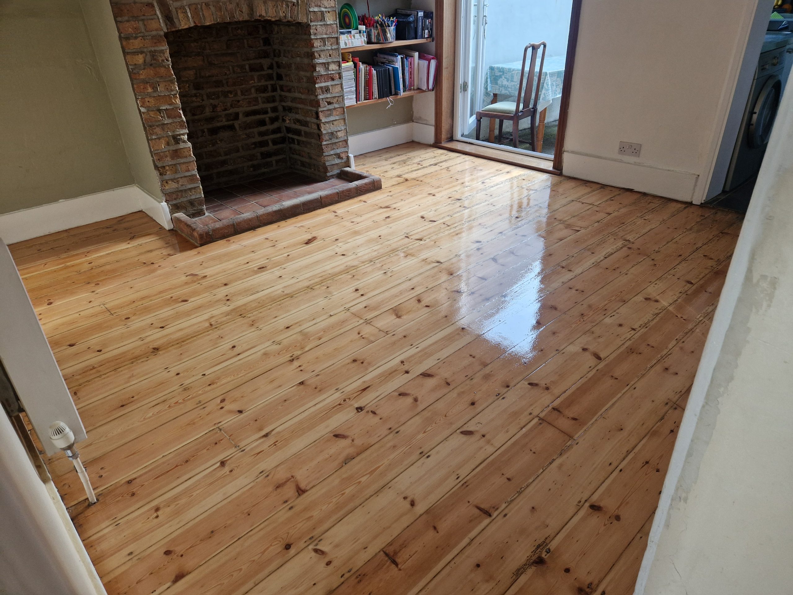 Freshly lacquered Victorian pine boards gleam in an Isleworth living room, the result of expert Transforming Victorian Boards.
