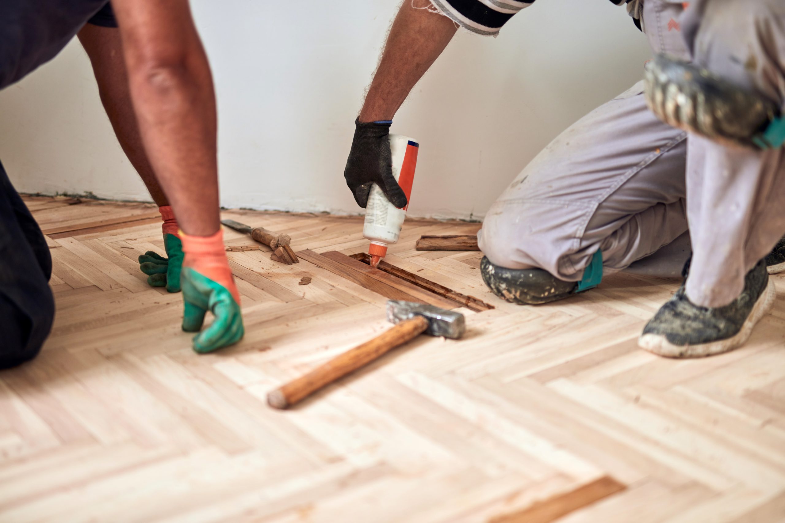 Heritage Parquet repair in Isleworth – technicians relaying oak herringbone parquet blocks with adhesive, ready for sanding and finishing.