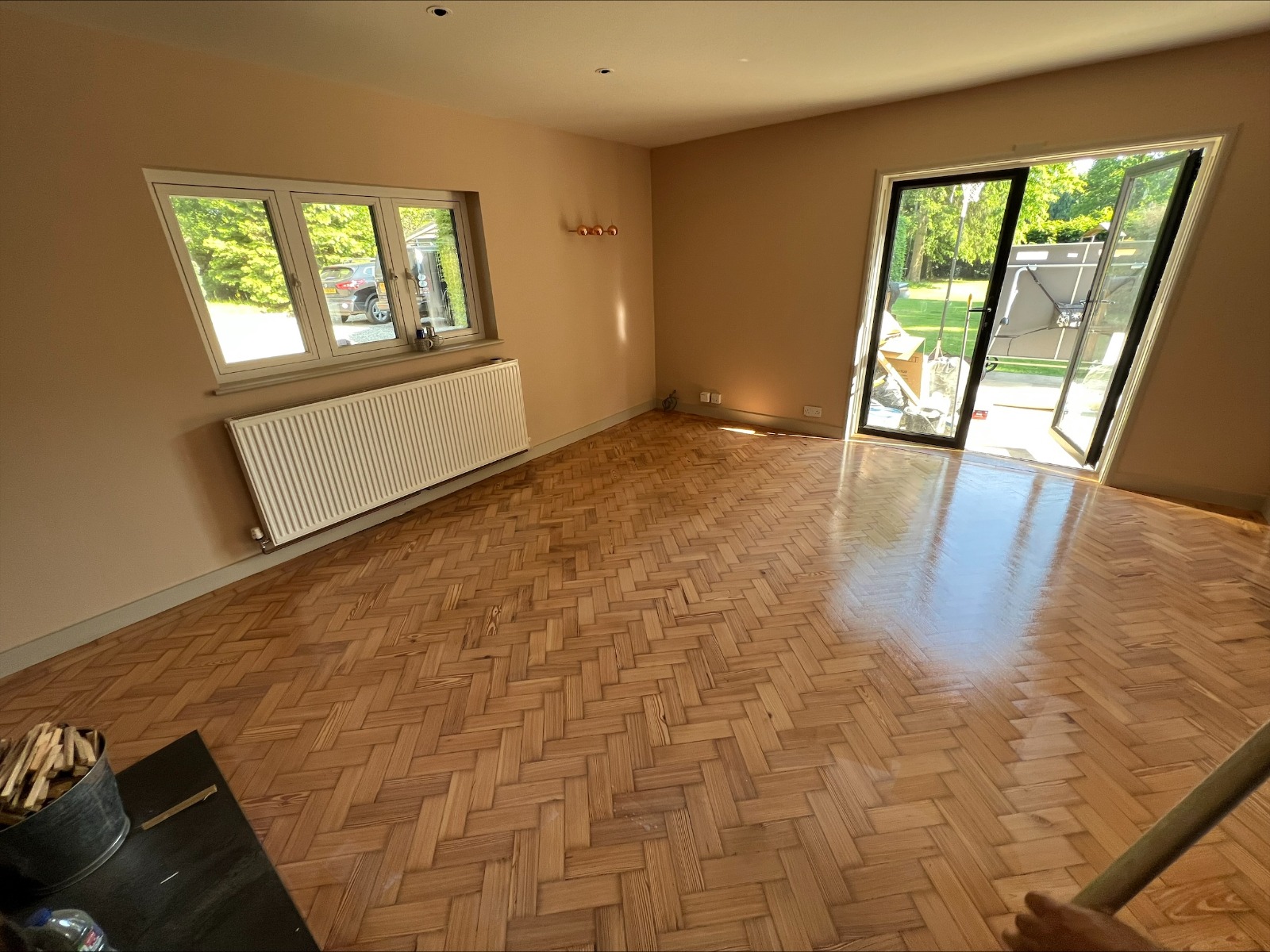 Heritage Parquet in Isleworth — freshly sanded and sealed oak herringbone parquet wood floor in a bright living room with patio doors.