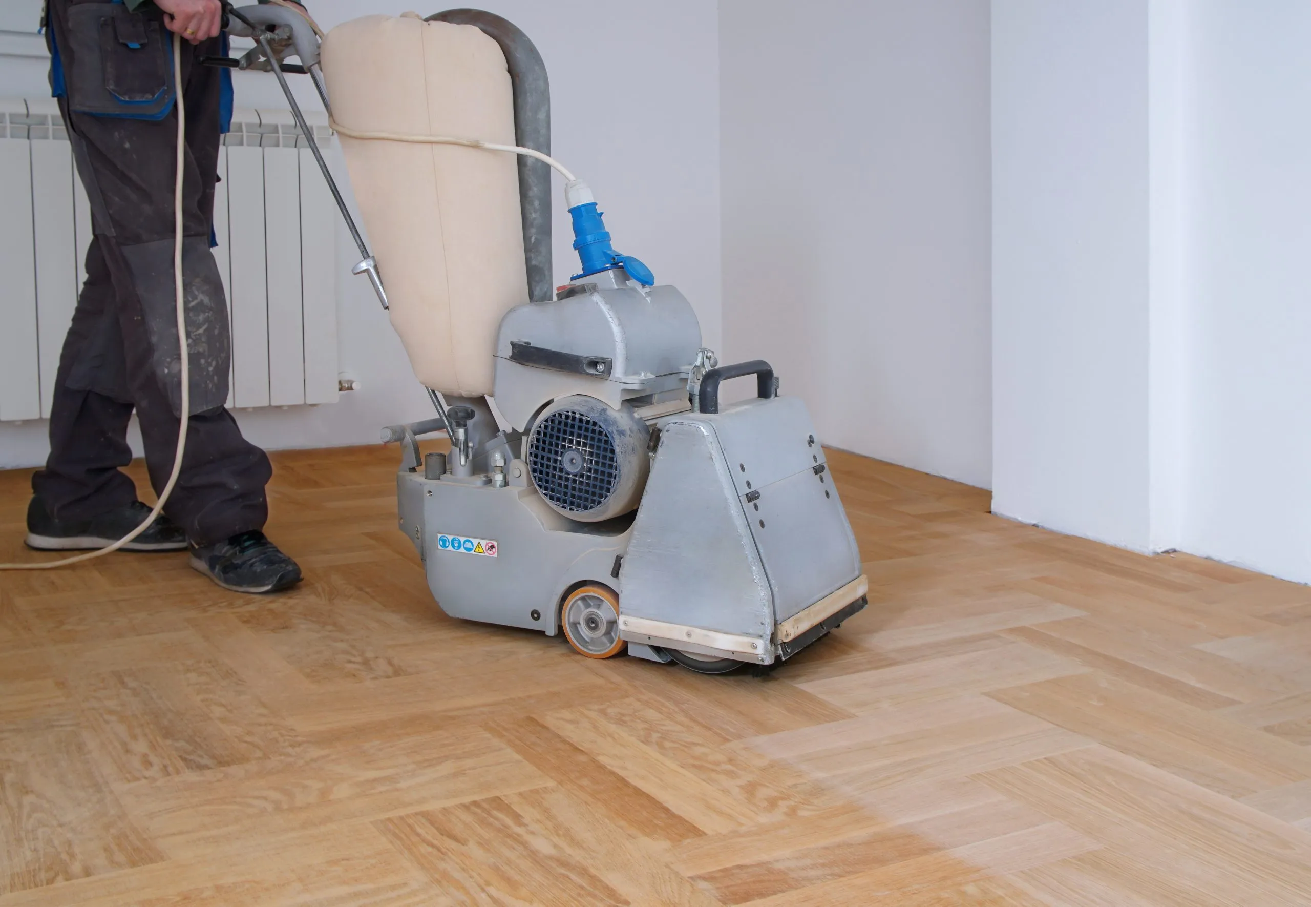 Wood Floor Sanding in Isleworth on light oak herringbone parquet flooring, with a professional floor sanding machine in use to smooth and refresh the timber surface.