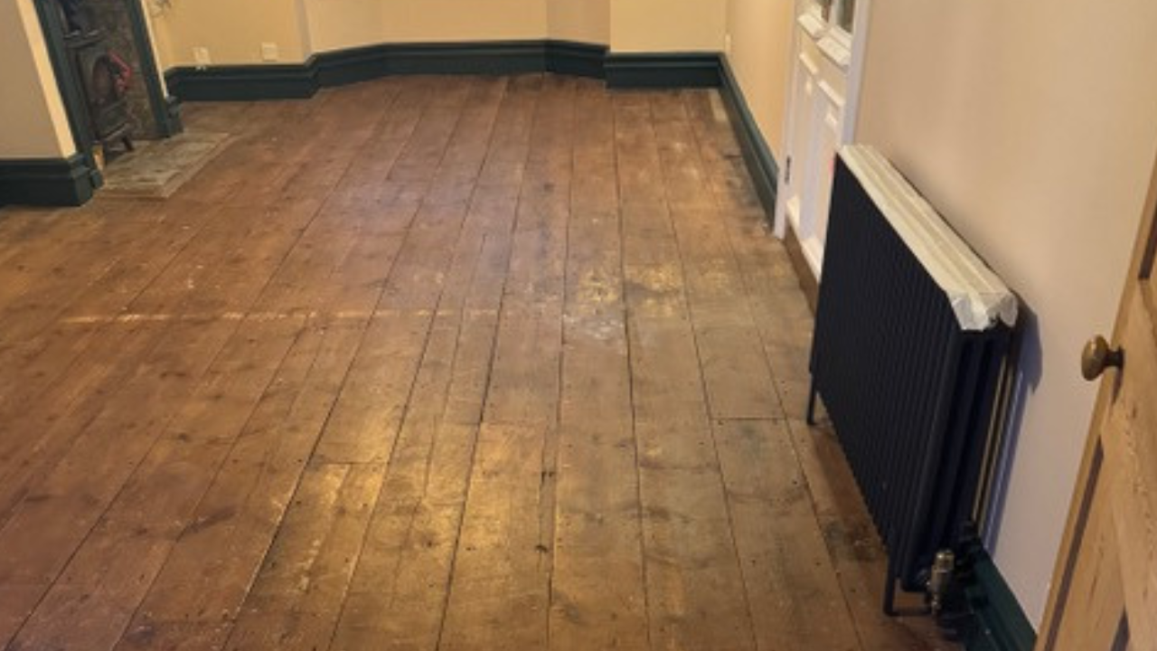 Before Wood Floor Sanding in an Isleworth living room, showing worn original softwood pine floorboards with dull, patchy finish ready for restoration.