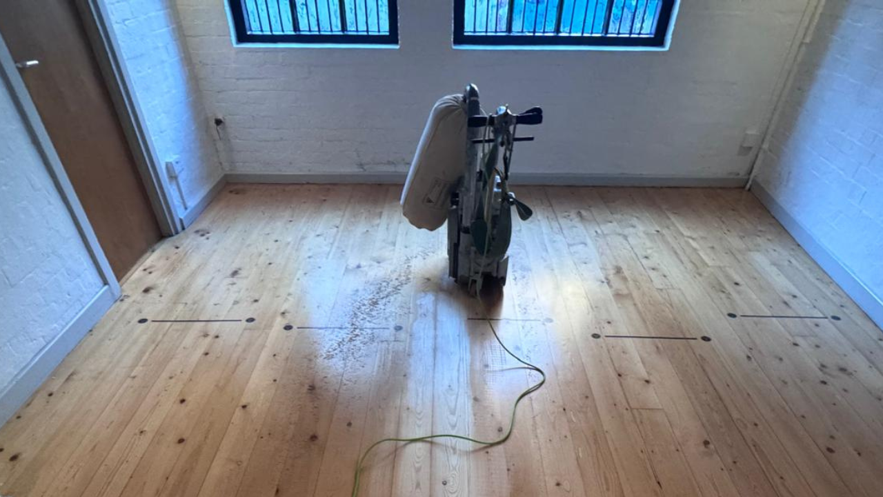 Wood Floor Sanding in an Isleworth room, showing pine softwood floorboards being professionally sanded with a belt sander in the centre of the floor.